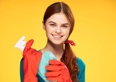 Deterjanlı temizlikçi kadın sarı arka planda.