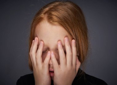 Siyah süveter giymiş, yüzünde çiller olan kızıl saçlı bir kız.