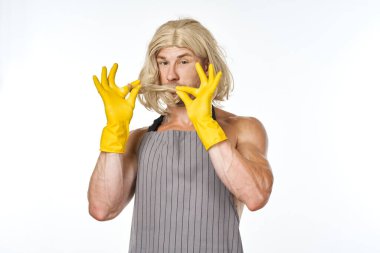 Sarı lastik eldivenli bir adam kadın peruğu temizleme pozu veriyor.