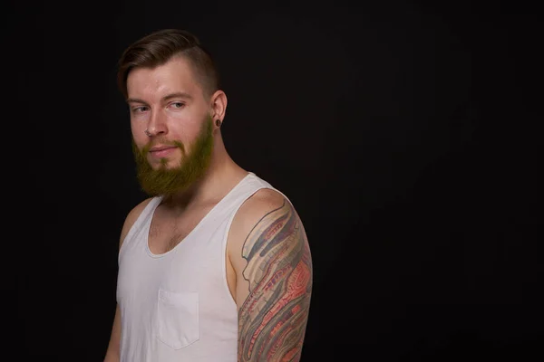 Man met baard met tatoeages op zijn armen gebaren met zijn handen donkere achtergrond — Stockfoto