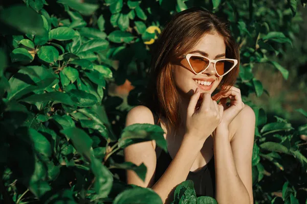 Sonriente mujer usando gafas de sol verde hojas naturaleza moda — Foto de Stock