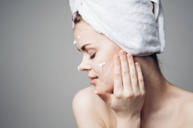 Çıplak omuzlu kadın yüz kremi sürmüş.