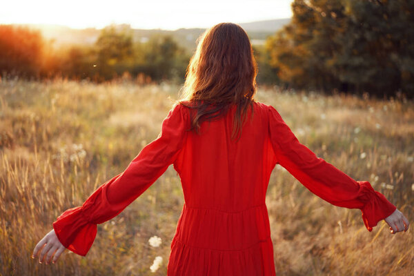 Woman in a red dress in a field in nature summer landscape freedom. High quality photo