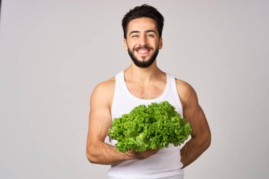 Beyaz tişörtlü neşeli adam marul sağlıklı yemek bırakıyor.