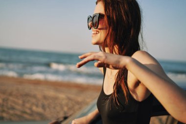 Kadın plajda güneş gözlüğü takan bir arabayla seyahat ediyor.