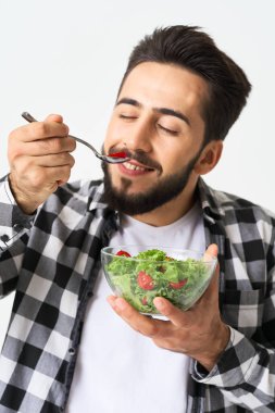 Ekose gömlekli bir adam sağlıklı salata yiyor.