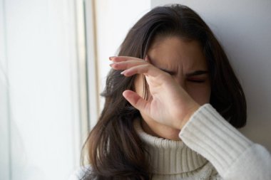 Üzgün kadın pencereden dışarı yakından bakıyor.