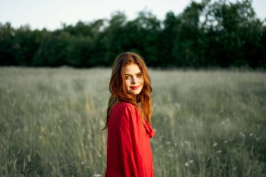 Kırmızılı güzel bir kadın doğada poz veriyor.