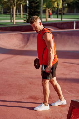 Sporcu adam dışarıda oyun sahasında spor yapıyor.