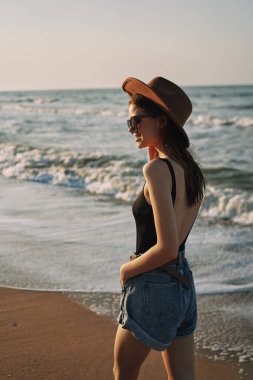 Kumsalda yürüyen bir kadın, tatil güneşinde seyahat ediyor.