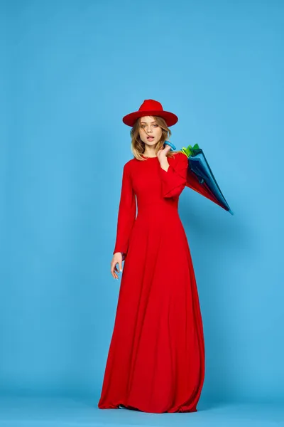 Kvinna i röd klänning flerfärgad paraply blå bakgrund — Stockfoto