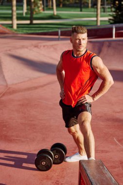 Sporcu adam dışarıda oyun sahasında spor yapıyor.