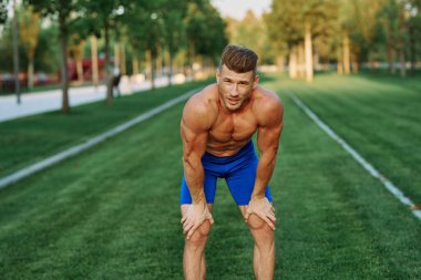 Parktaki spor egzersizinde şişirilmiş vücutlu bir sporcu.