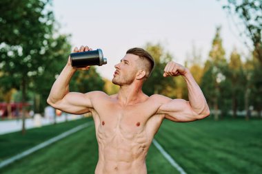 Parktaki egzersiz motivasyonunda kaslı vücutlu atletik bir adam.