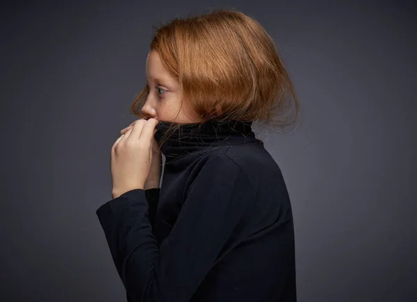Vörös hajú lány szeplőkkel az arcán fekete pulóverben pózol — Stock Fotó