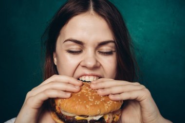 Hamburgerli neşeli kadın fast food yiyor.