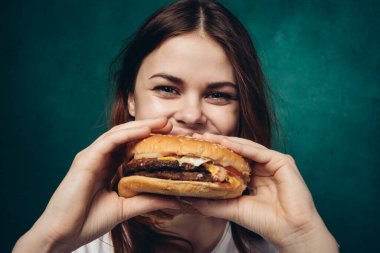 Hamburgerli neşeli kadın fast food yiyor.