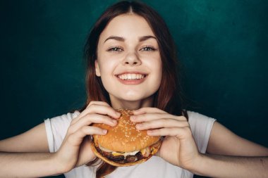 Hamburgerli neşeli kadın fast food yiyor.