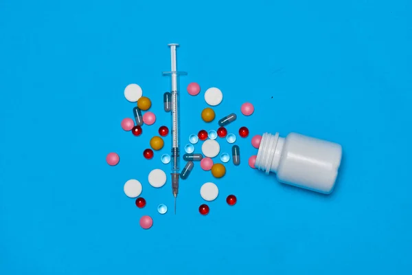 Pílulas multicoloridas tratamento de saúde estetoscópio fundo azul — Fotografia de Stock
