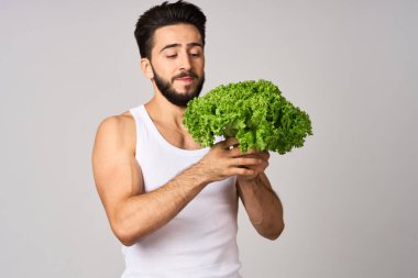 Beyaz tişörtlü sakallı adam marul yaprağı sebzeli sağlıklı yemek