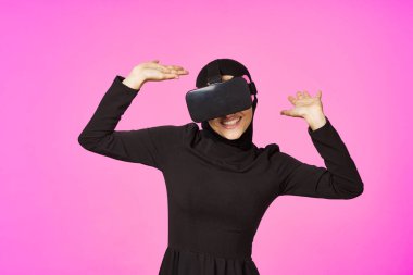 Siyah tesettürlü kadın gözlüklü sanal gerçeklik teknolojisi filmi izliyor