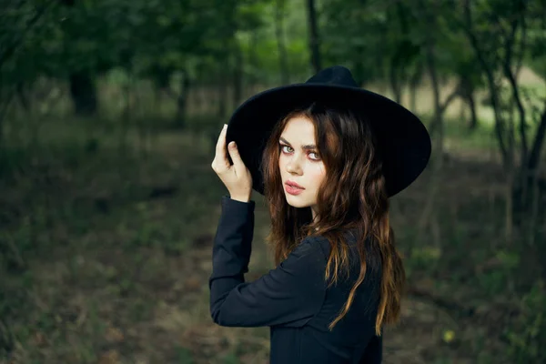 Mujer en el bosque en un traje de bruja de estilo gótico sombrero negro —  Fotos de Stock