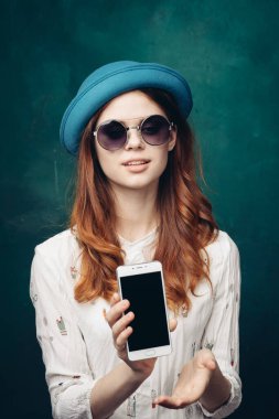 Mavi şapkalı şık bir kadın. Elinde telefon, iletişim teknolojisi var.