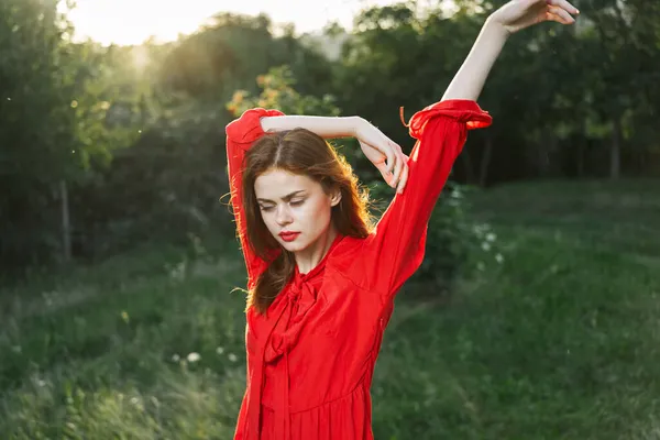 Mulher atraente em vestido vermelho posando na natureza grama verde — Fotografia de Stock