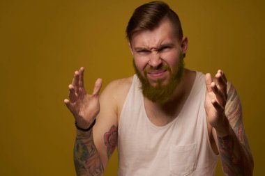 Kollarında holigan dövmeleri olan beyaz tişörtlü neşeli sakallı adam.