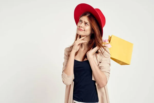 明るい女性が赤い帽子をかぶって買い物の楽しそうな光の背景をポーズ — ストック写真