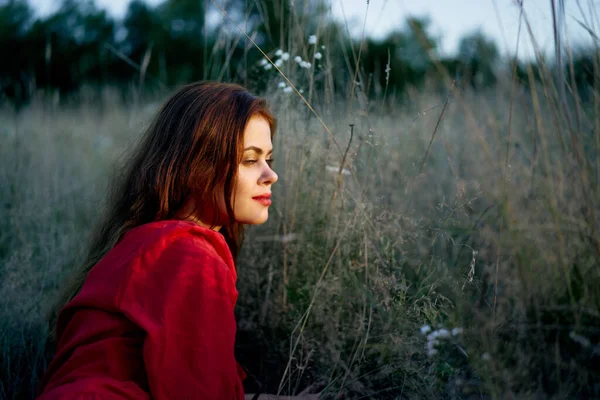 Kırmızı elbiseli güzel kadın çimen doğanın güneşinde yatıyor. — Stok fotoğraf