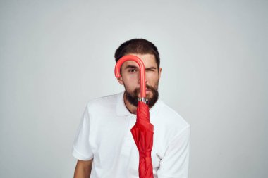 Kırmızı şemsiyeli adam yağmurdan korunuyor.