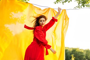 Sarı arka plan pozu veren kırmızı elbiseli çekici kadın.