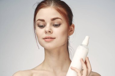 Çıplak omuzlu bir kadın cilt bakım kremi kullanıyor.