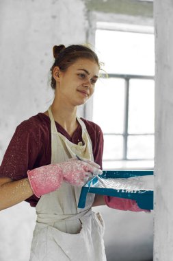 Beyaz önlüklü ev dekorasyonu yapan kadın ressam.