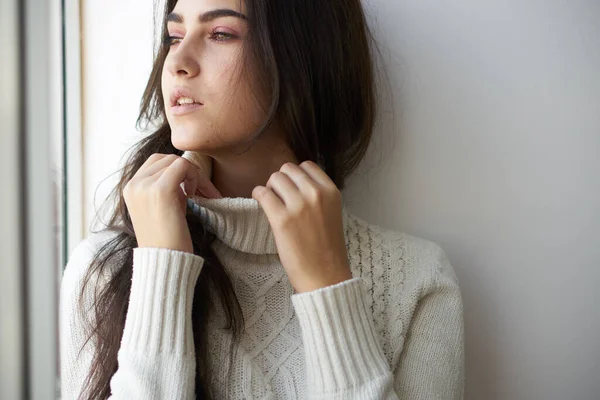 Mujer bonita en suéter blanco cerca de la ventana solo — Foto de Stock