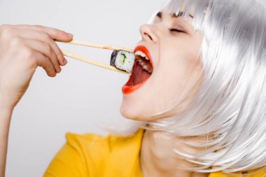 Beyaz peruklu güzel bir kadın ve Japon yemek çubuklarıyla suşi.