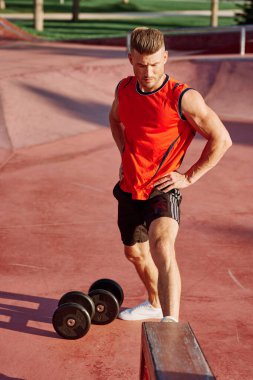 Sporcu adam dışarıda oyun sahasında spor yapıyor.