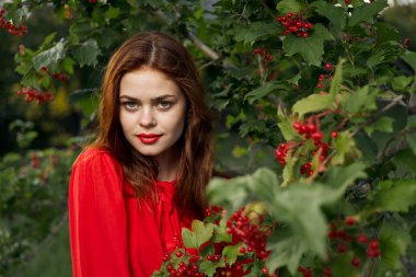 Kırmızı elbiseli güzel bir kadın yeşil yapraklı doğal yaz mevsimi.