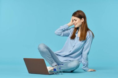 Dizüstü bilgisayarı olan bir kadın yerde oturmuş öğrenci teknolojisini öğreniyor.