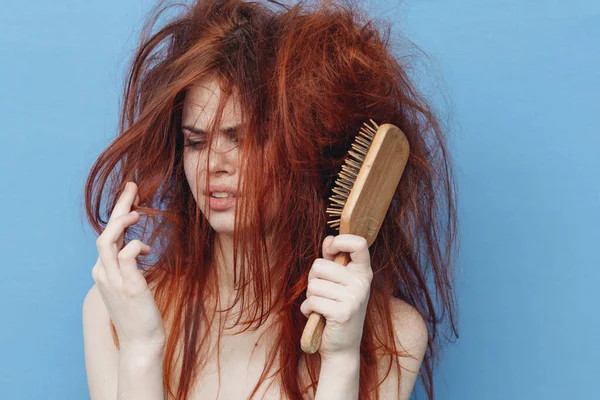 Kobieta z czerwonymi włosami grzebień opieki niebieskie tło — Zdjęcie stockowe