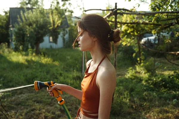 Vrouw water geven planten in de tuin platteland natuur teelt — Stockfoto