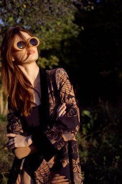Dışarıda güneş gözlüğü takan bir kadın moda cazibesi sergiliyor.