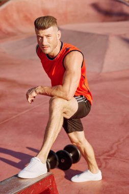 Sporcu adam dışarıda oyun sahasında spor yapıyor.