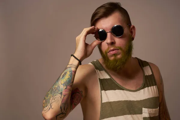 Бородатий чоловік у смугастій футболці з татуюваннями позує студію — стокове фото