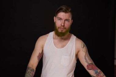 Kollarında dövmeleri olan sakallı bir adam.