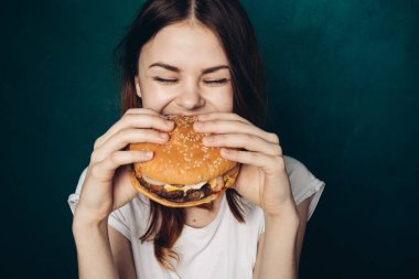 Hamburgerli neşeli kadın fast food yiyor.