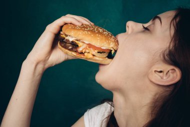 Hamburgerli neşeli kadın fast food yiyor.