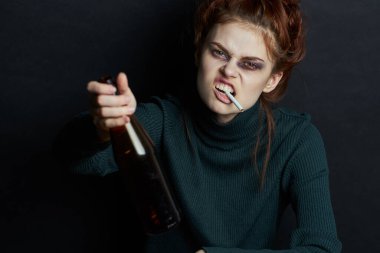 Bir şişe alkollü kadın sigara içiyor. Depresyon, göz altında morluklar.