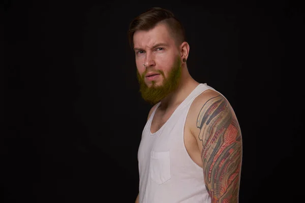 Бородатий чоловік у білій футболці з татуюваннями на руках позує знущання — стокове фото